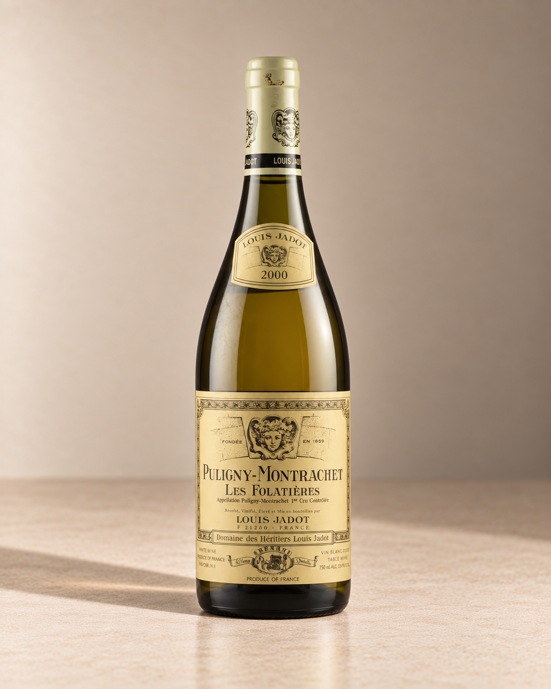 'Les Folatieres' Puligny Montrachet 1er Cru 2022 single wine bottle on a warm beige studio background